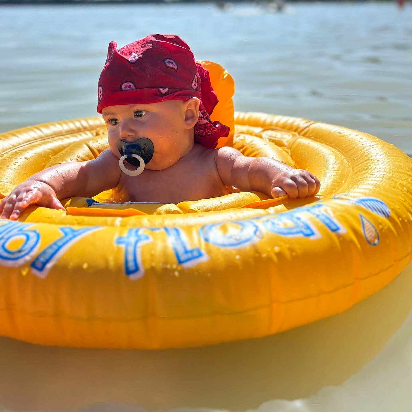 Kalvynn participe au concours pour gagner de l'argent avec cette photo : arm, baby, bandana, child, face, floating, head, inflatable_ring, lake, nature, outdoor, pacifier, recreation, red, relaxation, skin, summer, sunlight, water, yellow