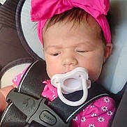 Lily joined the competition — help win amazing prizes! baby, pacifier, car_seat, pink_bow, blanket, child, infant, headband, seatbelt, clothing, cute, face, portrait, sitting, indoors, young_child, safety, resting, expression, toddler