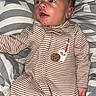 baby, infant, onesie, striped_clothing, milk_patch, cookie_patch, blanket, patterned_blanket, lying_down, curious_expression, hair_tuft, cozy, indoor, child, newborn, sleepwear, soft_fabric, cute, portrait, young_child
