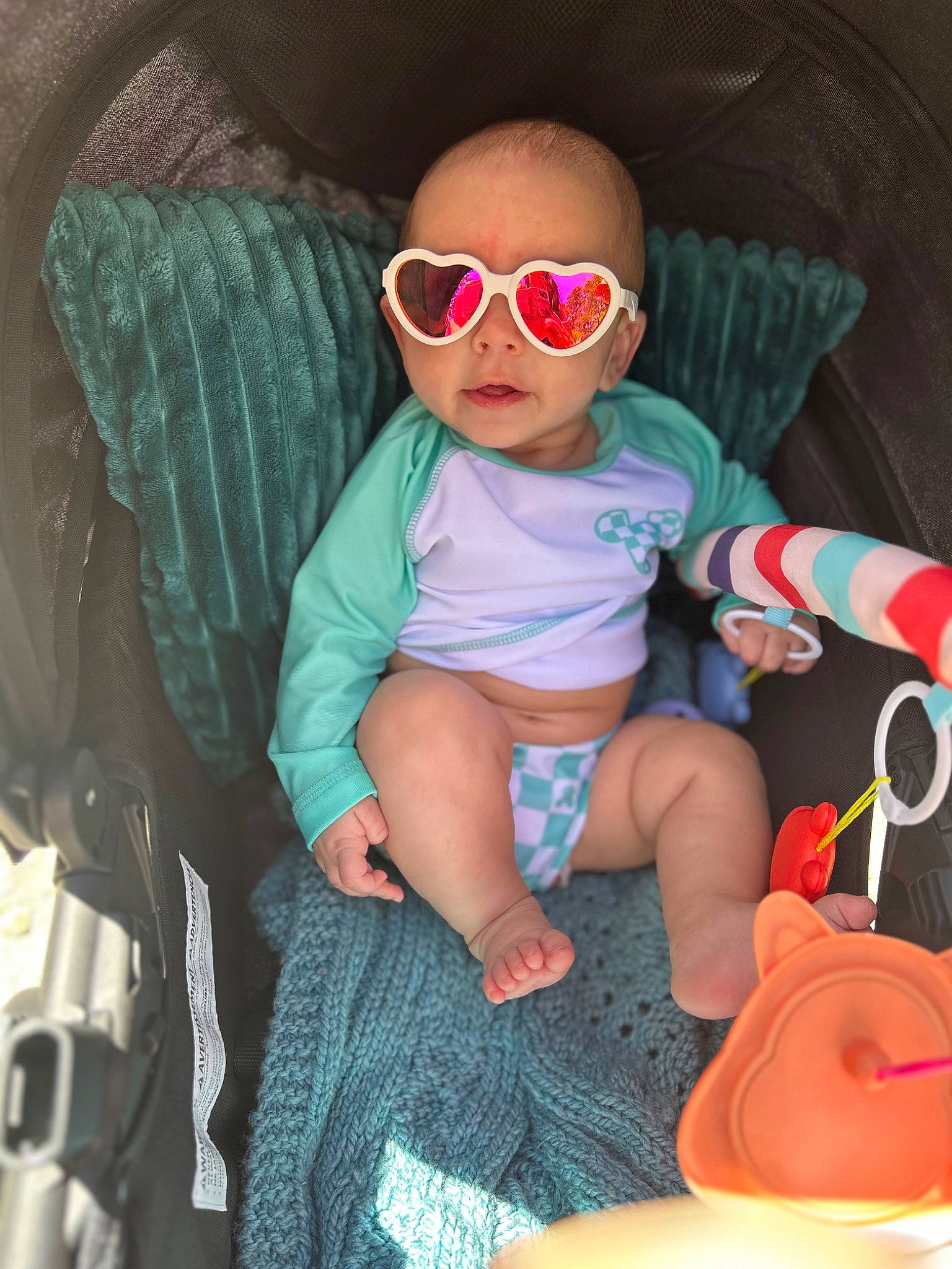Adaline is registered to the contest to win money with this photo: baby, baby_products, baby_toddler_clothing, child, comfort, eyewear, fun, glasses, goggles, hat, lap, people, person, personal_protective_equipment, pink, sitting, sun_hat, sunglasses, thigh, toddler