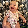 Raelynn is registered to the contest to win money with this photo: baby, smiling, infant, onesie, floral_pattern, blanket, elephant_pattern, cheerful, sitting, dimples, soft_texture, indoors, cute, happy, child, person, cozy, warm, comfortable, bright