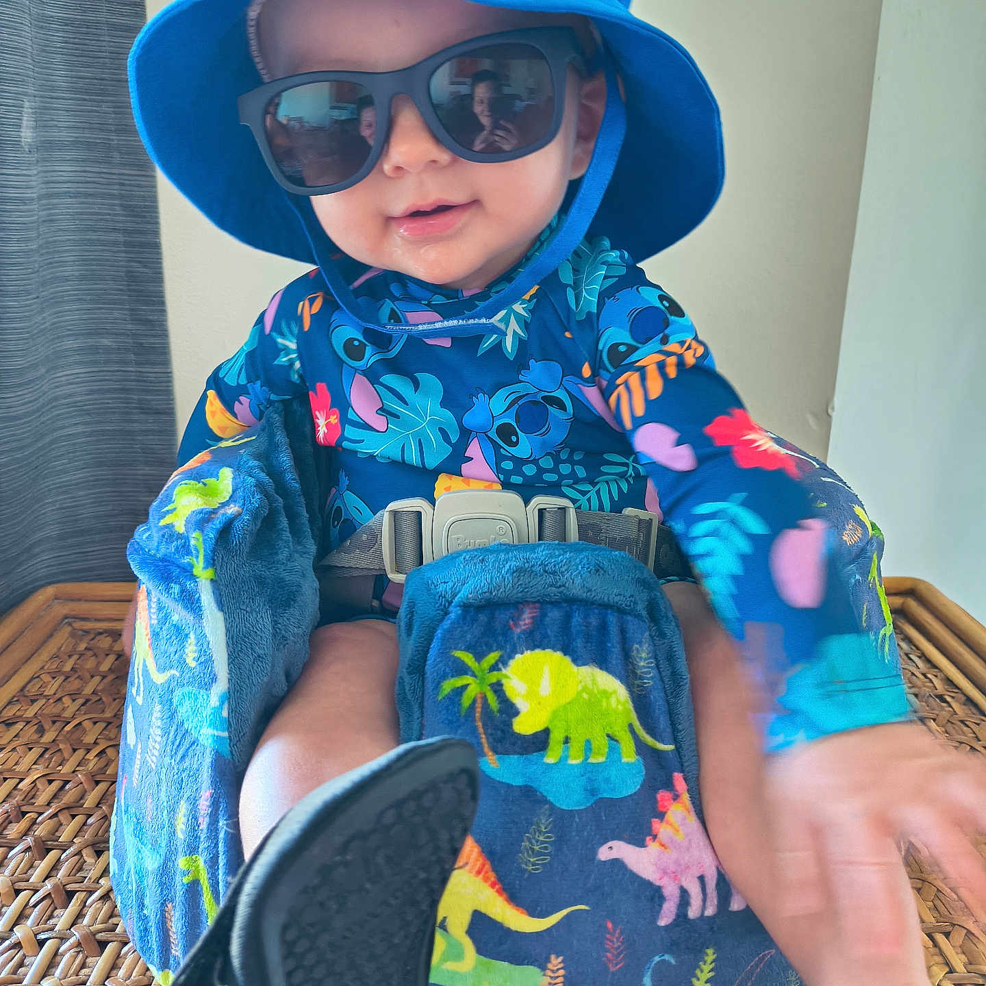 Bentlee joined the competition — help win amazing prizes! toddler, child, baby, blue_hat, sunglasses, booster_seat, dinosaur_pattern, colorful_clothing, indoor, woven_surface, smiling, reaching_hand, seatbelt, playful, cute, portrait, person, hat, footwear, bright_colors