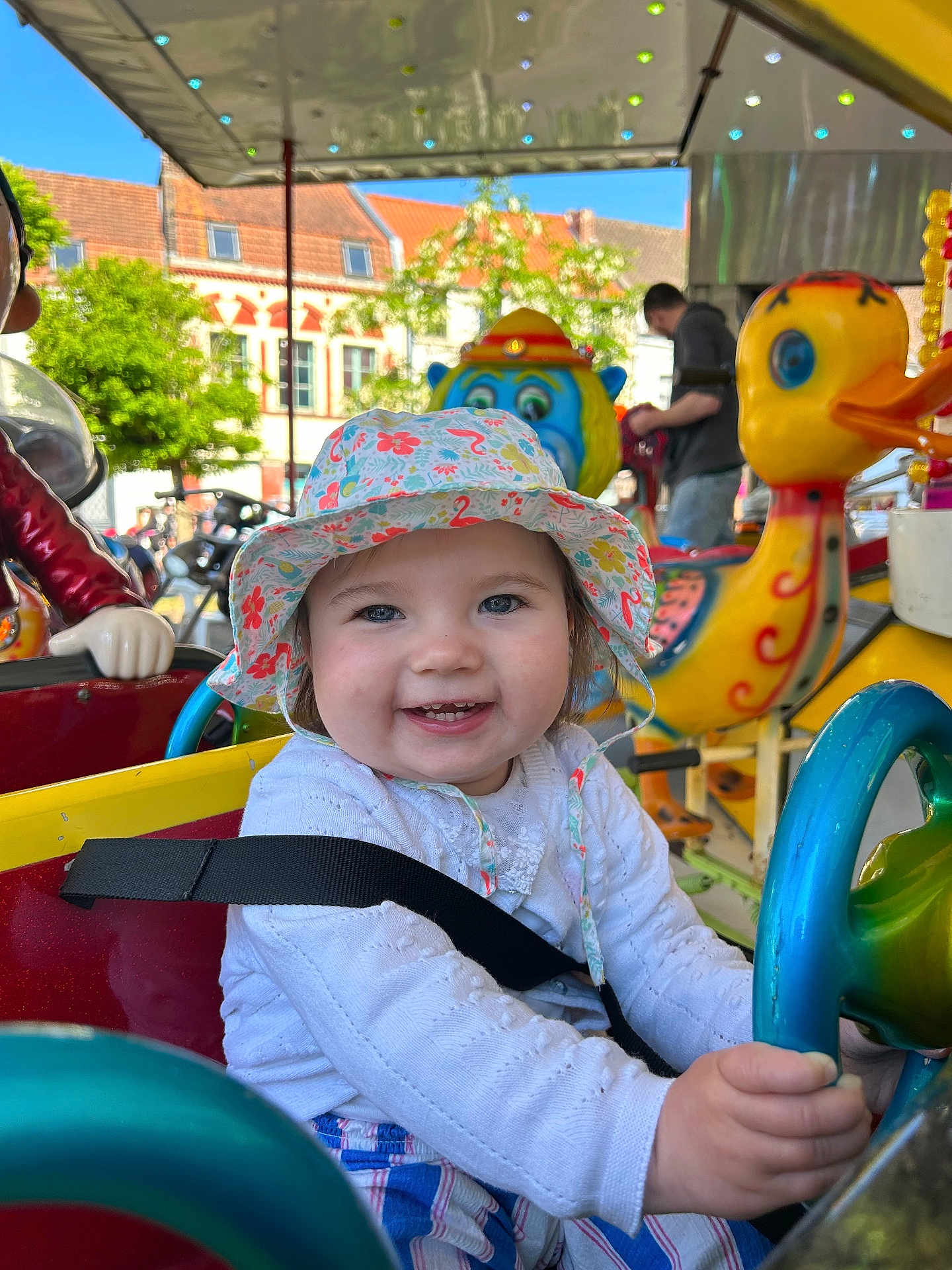 Lylia participe au concours pour gagner de l'argent avec cette photo : child, toddler, hat, smile, blue_eyes, carousel, ride, toy_duck, toy_monkey, outdoor, sunny, daylight, playful, colorful, seatbelt, clothing, person, amusement_ride, happy, fun