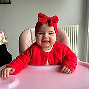 Lylia participe au concours pour gagner de l'argent avec cette photo : baby, child, high_chair, red_headband, red_sweater, smiling, toothy_grin, indoor, pink_high_chair, cute, happy, portrait, person, headwear, infant, clothing, furniture, baby_girl, sitting, cheerful