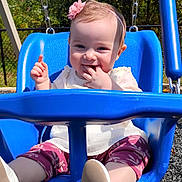Kaeli Rose joined the competition — help win amazing prizes! baby, child, swing, playground, blue_swing, smiling, headband, flower, outdoor, sunny, grass, trees, clothing, happy, infant, person, seat, footwear, nature, play