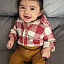 baby, child, smiling, red_shirt, checkered_shirt, mustard_pants, white_socks, couch, gray_couch, happy, indoor, portrait, infant, clothing, sitting, cute, young_child, face, person, casual