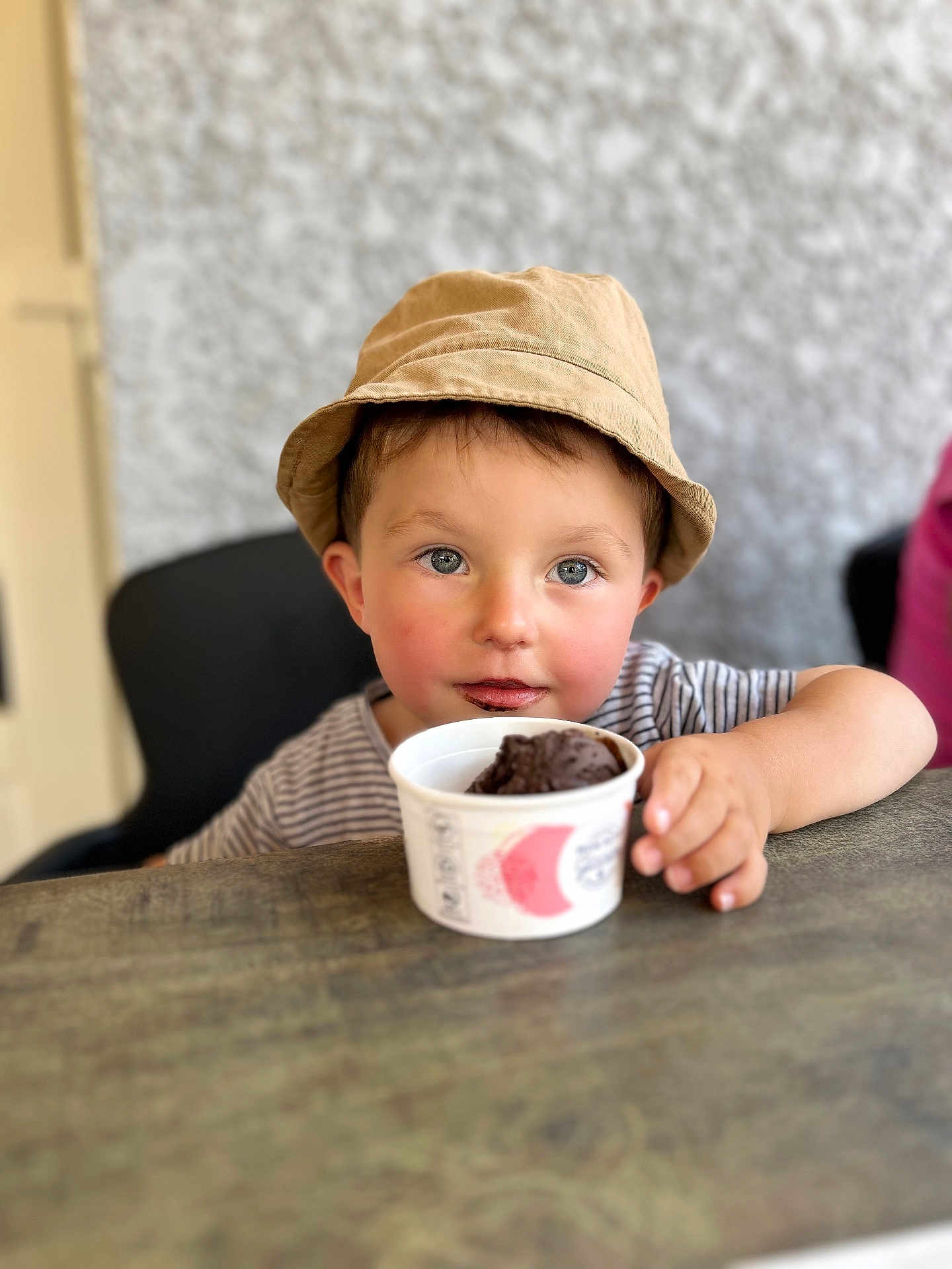 Xuann a rejoint le concours — aidez-le/la à gagner de superbes lots ! child, toddler, hat, bucket_hat, striped_shirt, chocolate_ice_cream, cup, table, face, eyes, hand, indoor, food, dessert, sweet, cute, smile, messy, person, portrait