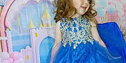 Delilah is registered to the contest to win money with this photo: balloons, blue_dress, bow, castle, celebration, child, costume, curly_hair, cute, dress, event, fashion, girl, golden_embroidery, happy, indoor, party_backdrop, portrait, smiling, tulle