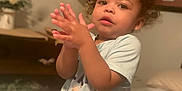 Trenton joined the competition — help win amazing prizes! toddler, child, indoor, curly_hair, clapping, bedroom, lamp, flowers, pillow, blanket, person, cute, young_child, casual_clothing, portrait, expression, soft_light, home, furniture, relaxed