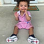 Trenton is registered to the contest to win money with this photo: toddler, child, curly_hair, smiling, snack, striped_clothing, sneakers, porch, concrete_floor, doormat, door, glass, outdoor, happy, sitting, casual, fashion, person, young_child, daylight