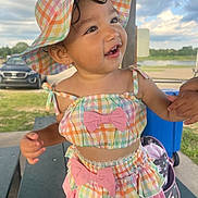 Adela joined the competition — help win amazing prizes! car, child, colorful_clothing, cute, daylight, earring, hand_holding, happy, hat, nature, outdoor, park, picnic_table, plaid, skirt, sky, smiling, summer, toddler, top