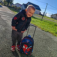 Mayven participe au concours pour gagner de l'argent avec cette photo : child, boy, outdoor, sunny, backpack, spiderman, jacket, shoes, smiling, pavement, grass, house, fence, blue_sky, casual_clothing, young, happy, daytime, person, toy