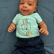 Saël a rejoint le concours — aidez-le/la à gagner de superbes lots ! baby, big_cats, blanket, blue_shirt, cargo_pants, casual_clothing, child, closeup, cute, dark_pants, fists, graphic_tee, happy, indoors, infant, lying_down, person, portrait, smiling, young_child