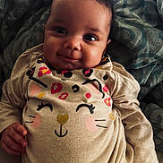 Ivori is registered to the contest to win money with this photo: baby, infant, smile, face, clothing, onesie, cute, child, pattern, blanket, lying, happy, person, young, indoor, portrait, hand, cozy, soft, animal_print