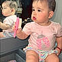 baby, child, mirror, reflection, brush, pink, tshirt, skirt, hair_accessory, vanity, makeup, furniture, indoor, cute, portrait, sitting, expression, face, person, lighting