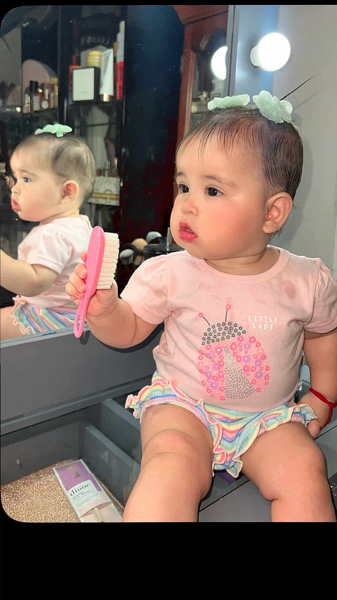 Cindy joined the competition — help win amazing prizes! baby, child, mirror, reflection, brush, pink, tshirt, skirt, hair_accessory, vanity, makeup, furniture, indoor, cute, portrait, sitting, expression, face, person, lighting