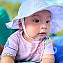 baby, child, hat, white_hat, dinosaur_shirt, pastel_colors, close_up, portrait, outdoor, blue_sky, curious, chubby_arms, cute, soft_focus, summer, sun_hat, infant, wide_eyes, casual_clothing, daylight