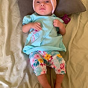 Alessia a rejoint le concours — aidez-le/la à gagner de superbes lots ! baby, barefoot, bed, blue_shirt, child, curious, fabric, floral_pants, headband, human, indoors, infant, lying_down, pacifier, person, pillow, pink, sleepwear, soft_lighting, toddler