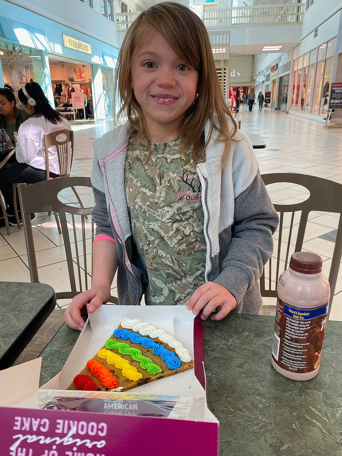 Ryleigh is registered to the contest to win money with this photo: artist, bottle, box, chair, child, drink, event, fun, joy, leisure, office_supplies, person, plastic_bottle, play, recreation, room, smile, t_shirt, table, tin_can