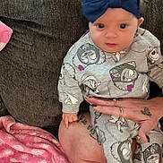 Skye is registered to the contest to win money with this photo: baby, child, infant, headband, bow, clothing, cartoon, pattern, couch, blanket, tattoo, hand, rings, person, indoor, seated, cute, portrait, fabric, soft