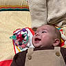 baby, blanket, buttons, cheek, colorful, ear, face, gaze, happy, indoor, infant, mouth_open, onesie, overalls, patterned_sheet, photography, play_mat, smile, soft_texture, toy