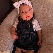 Alma a rejoint le concours — aidez-le/la à gagner de superbes lots ! baby, child, infant, headband, bow, denim_overalls, white_shirt, cushion, chair, indoor, person, skin, face, legs, hand, clothing, cute, expression, portrait, comfort
