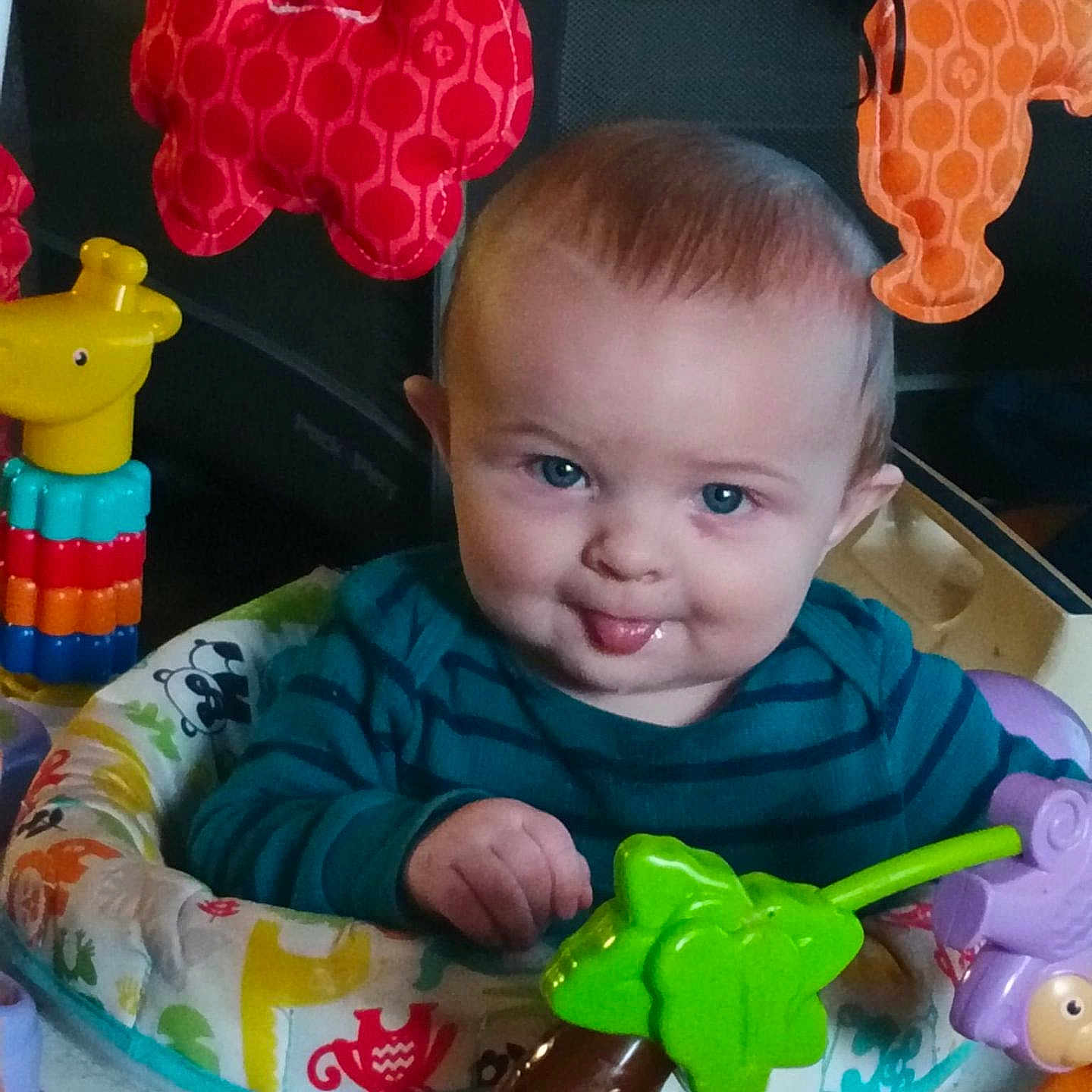 Scottie joined the competition — help win amazing prizes! activity_center, baby, blue_eyes, child, colorful, cute, expression, face, giraffe_toy, hand, indoor, infant, playful, plush_toy, seat, smiling, striped_shirt, tongue_out, toys, young_child
