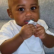 Jelani a rejoint le concours — aidez-le/la à gagner de superbes lots ! baby, big_eyes, chewing, child, close_up, couch, curly_hair, cute, diaper, hands, indoor, living_room, pacifier, portrait, sitting, skin, smiling_ish, sofa, toddler, white_shirt