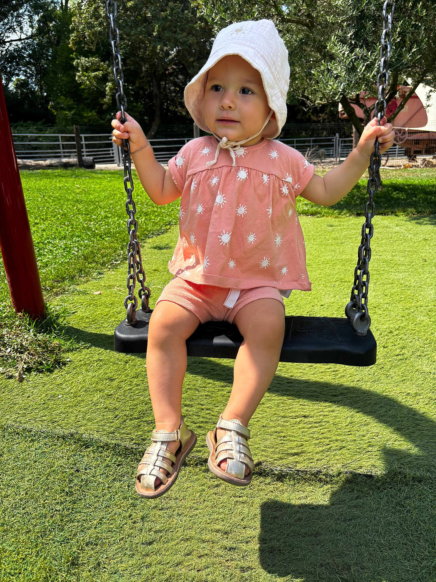 Maylie participe au concours pour gagner de l'argent avec cette photo : toddler, child, swing, hat, outdoor, grass, playground, sunlight, summer, pink_clothing, sandals, trees, chains, expression, cute, baby, nature, fun, daylight, park