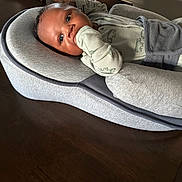 Kj joined the competition — help win amazing prizes! baby, infant, baby_nest, gray, wooden_table, clothing, sleeve, face, hand, curious, indoors, person, newborn, baby_garment, resting, child, young, portrait, cozy, furniture