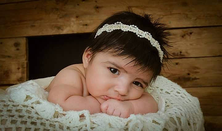 Shaihyli participe au concours pour gagner de l'argent avec cette photo : baby, baby_toddler_clothing, bridal_accessory, comfort, embellishment, eye, eyebrow, eyelash, face, flash_photography, grass, happy, headband, headpiece, iris, linens, person, picture_frame, skin, smile