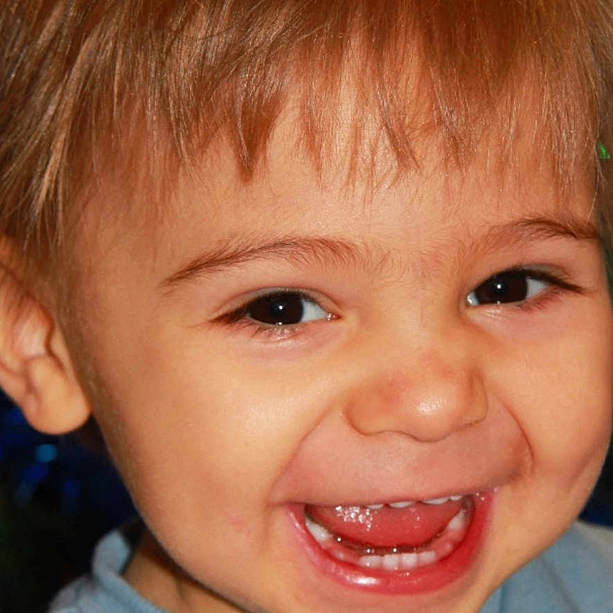 Marius a rejoint le concours — aidez-le/la à gagner de superbes lots ! background_blur, blue_shirt, child, christmas_lights, closeup, cute, expression, face, happy, holiday, indoors, joyful, light_brown_hair, person, photography, portrait, screen_overlay, smiling, teeth, toddler
