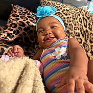 Iridessa joined the competition — help win amazing prizes! baby, smile, headband, flower, striped_clothing, leopard_print, pillow, blanket, hand, face, infant, happy, cute, indoors, child, portrait, cozy, colorful, person, soft