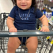 Landon is registered to the contest to win money with this photo: toddler, child, shopping_cart, smile, blue_shirt, necklace, hair_tie, supermarket, aisle, adult_hand, plaid_shirt, legs, barefoot, metal_cart, retail, casual_clothing, cute, portrait, indoor, happy