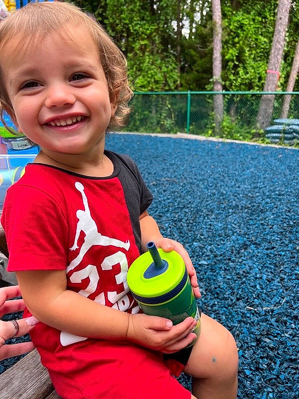 Robert is registered to the contest to win money with this photo: baby_toddler_clothing, child, finger, fun, gesture, grass, hand, happy, joy, leisure, people_in_nature, person, plant, play, recreation, smile, sports_toy, standing, t_shirt, toddler