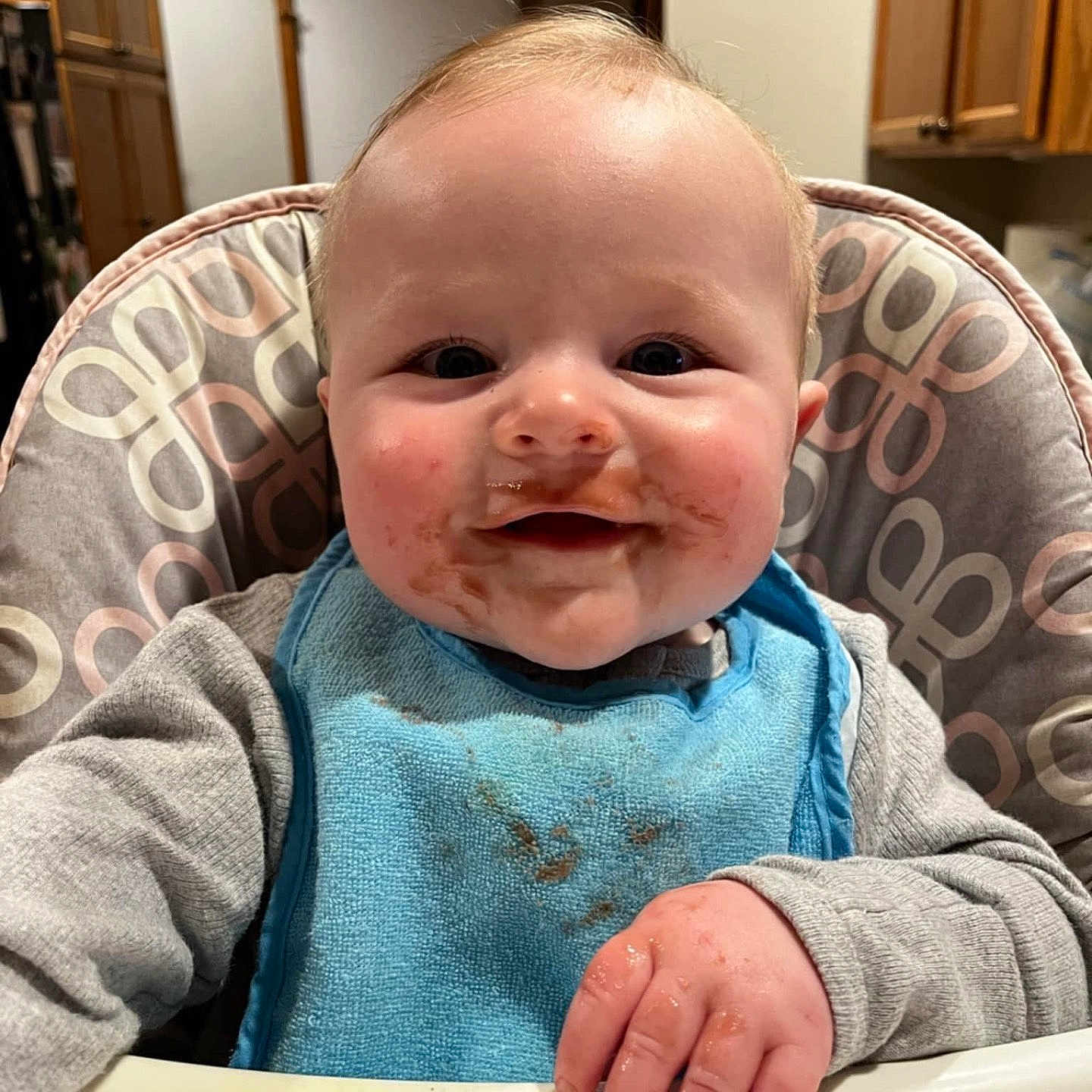 Kaysen is registered to the contest to win money with this photo: baby, babylaughing, bib, chair, clothing, coat, cutlery, face, furniture, happy, head, laughing, person, photography, plant, portrait, pottedplant, sitting, smile, spoon