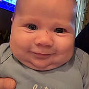 Jett is registered to the contest to win money with this photo: baby, child, smiling, face, onesie, clothing, hand, indoor, portrait, cute, chubby_cheeks, little_brother, infant, human, person, expression, holding, background, screen, home