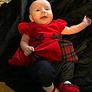 Emberly joined the competition — help win amazing prizes! baby, child, smile, red_dress, plaid, shoes, sock, lying_down, happy, infant, cute, portrait, indoors, blanket, clothing, person, young_child, arm, footwear, face