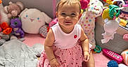 Eliana joined the competition — help win amazing prizes! baby, child, pink_dress, playpen, plush_toys, stuffed_animals, toy_mobile, pink_mat, smiling, indoor, cute, infant, floor_mat, colorful, toddler, soft_toys, play_area, happy, girl, young_child