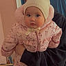 Eliana is registered to the contest to win money with this photo: baby, child, infant, hat, bear_ears, pink_snowsuit, floral_pattern, person, indoor, curious, holding, jacket, warm_clothing, cute, face, portrait, winter_wear, headwear, hands, cozy