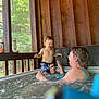 Kyler James joined the competition — help win amazing prizes! child, toddler, adult, woman, hot_tub, water, swimwear, wooden_wall, window, outdoor, nature, trees, cabin, laughing, playing, summer, relaxation, family, fun, bubbles