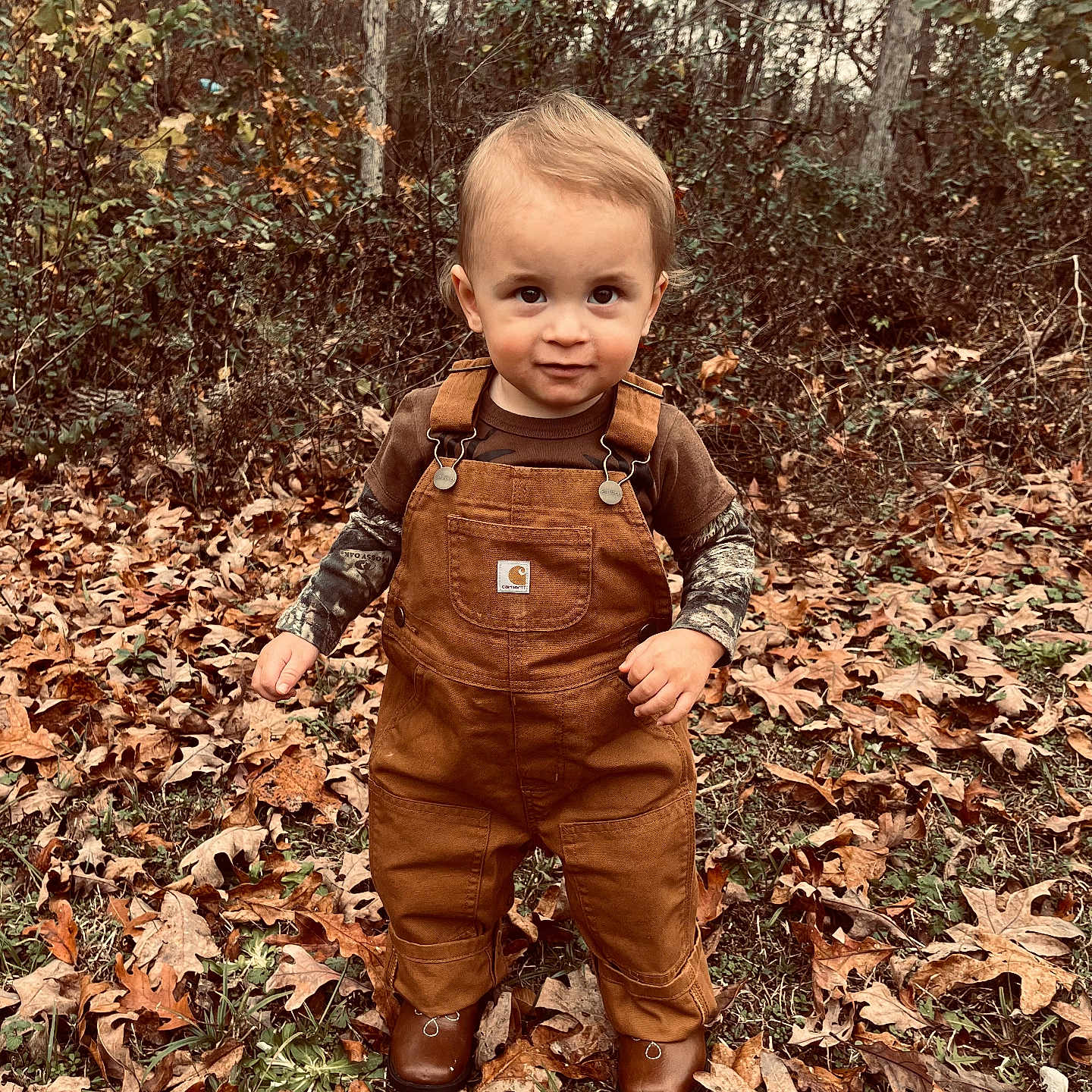 Kyler James joined the competition — help win amazing prizes! autumn_leaves, boots, brown_clothing, casual, child, cute, fall, forest, grass, leaves, nature, outdoor, overalls, person, portrait, seasonal, standing, toddler, trees, young_child