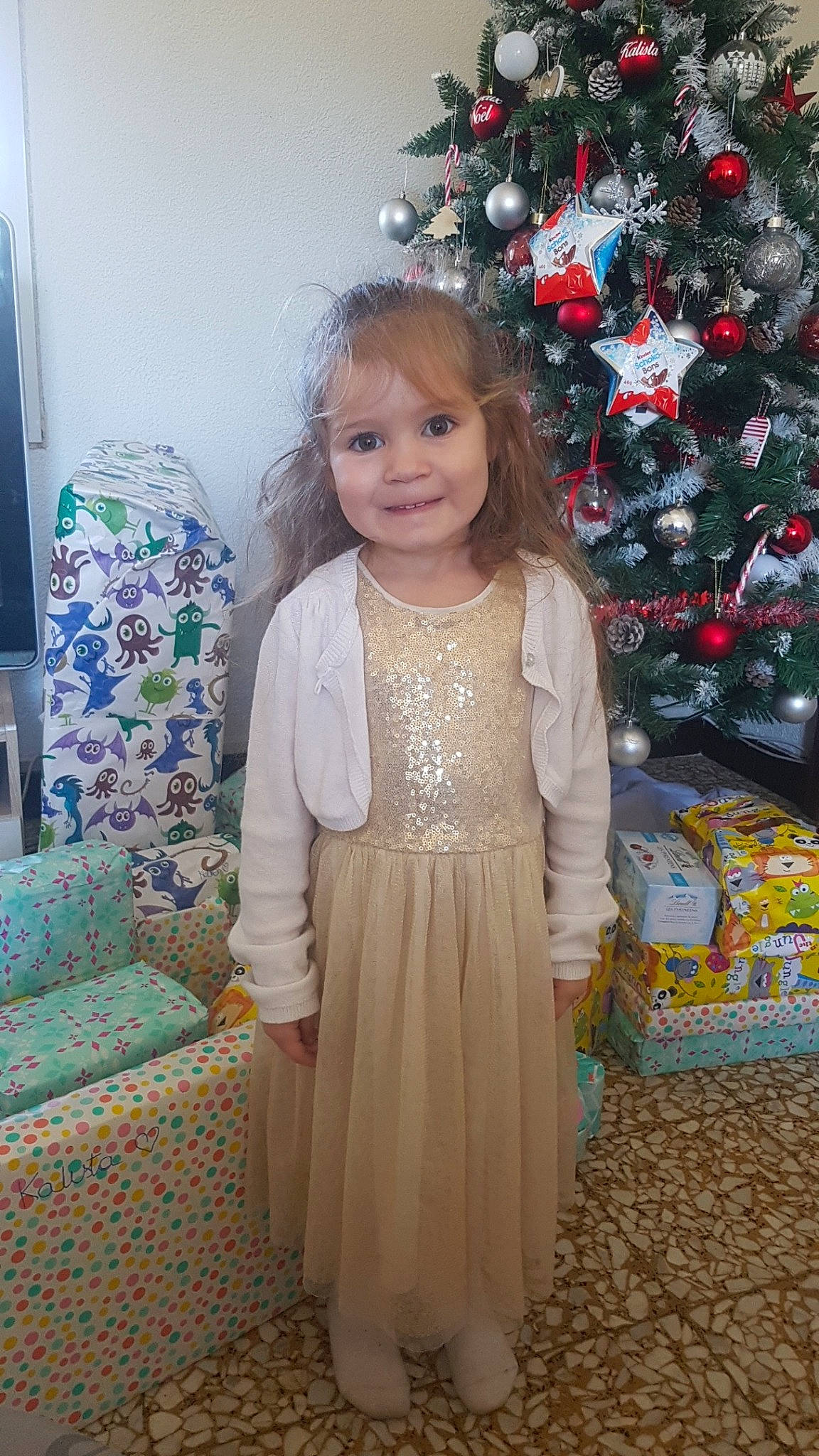 Kalista participe au concours pour gagner de l'argent avec cette photo : child, christmas, christmas_decoration, christmas_eve, christmas_tree, dress, event, family, holiday, interior_design, joy, outerwear, person, smile, standing, toddler