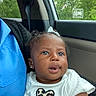 baby, blue_shirt, car_interior, car_seat, child, curly_hair, cute, daylight, earrings, greenery, heart, infant, leopard_print, person, portrait, seatbelt, skin, smile, white_shirt, window