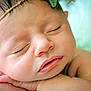 baby, sleeping, close_up, face, headband, hand, skin, infant, peaceful, resting, soft_lighting, portrait, newborn, cute, child, expression, relaxed, indoors, smooth_skin, young
