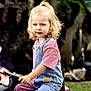 Romy participe au concours pour gagner de l'argent avec cette photo : child, toddler, blonde_hair, pony_tail, denim_overalls, pink_shirt, toy_vehicle, outdoor, greenery, grass, tree, garden, play, cute, young_child, portrait, person, daylight, smile, happy