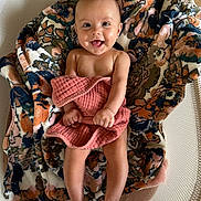 Navy is registered to the contest to win money with this photo: baby, smiling, blanket, floral_pattern, pink_cloth, basket, woven, happy, infant, cute, skin, bare_chest, legs, feet, indoor, wood_floor, cozy, portrait, child, expression