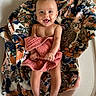 baby, smiling, blanket, floral_pattern, pink_cloth, basket, woven, happy, infant, cute, skin, bare_chest, legs, feet, indoor, wood_floor, cozy, portrait, child, expression