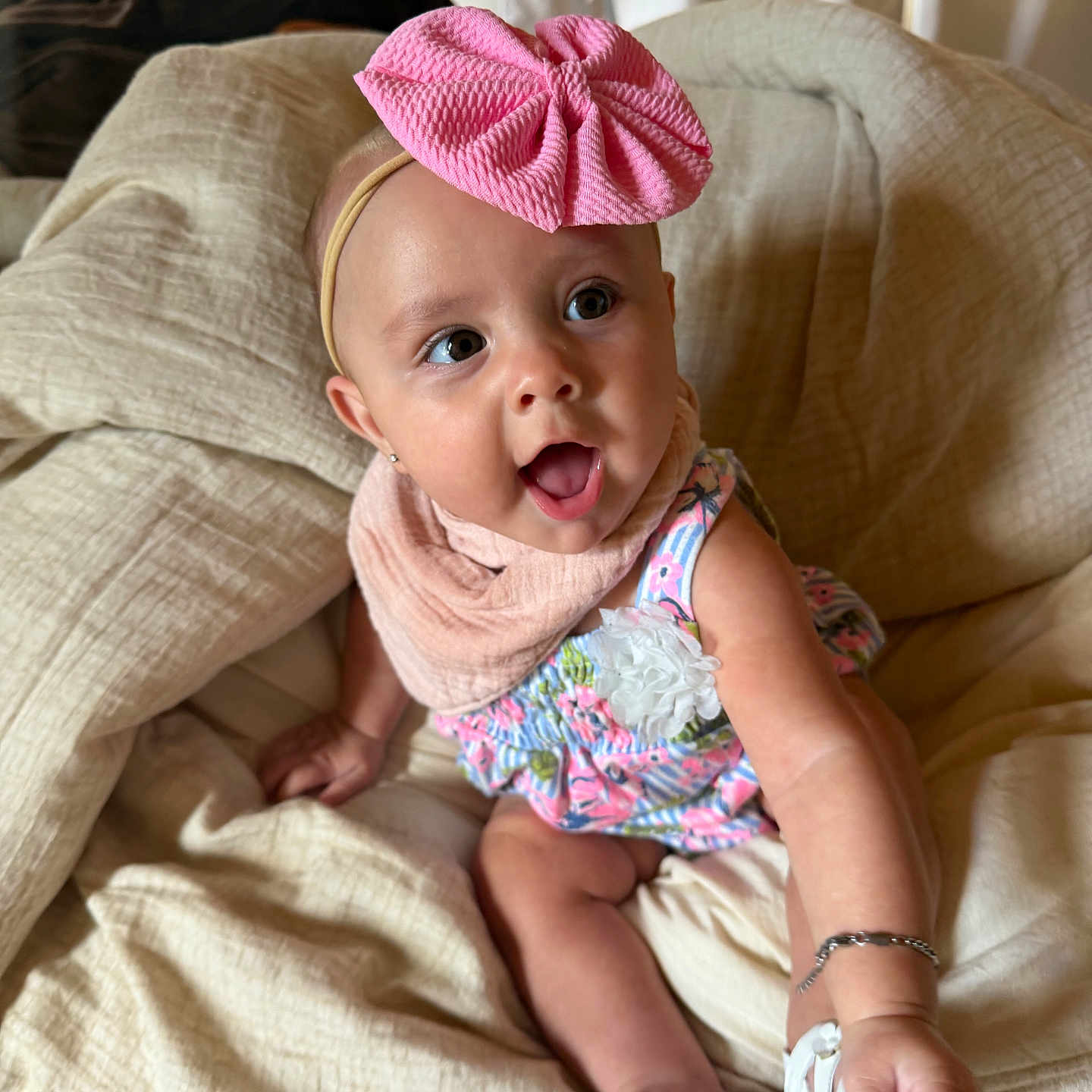 Navy joined the competition — help win amazing prizes! baby, child, infant, pink_bow, headband, floral_dress, bracelet, blanket, smiling, happy, indoors, person, cute, sitting, footwear, white_sandals, face, eyes, hand, soft_lighting