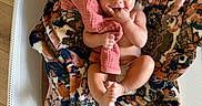 Navy is registered to the contest to win money with this photo: baby, bassinet, blanket, child, cute, eyes, face, fingers, floral_blanket, foot, hand, indoors, infant, lying_down, mesh_bassinet, mouth, person, pink_cloth, skin, wooden_floor